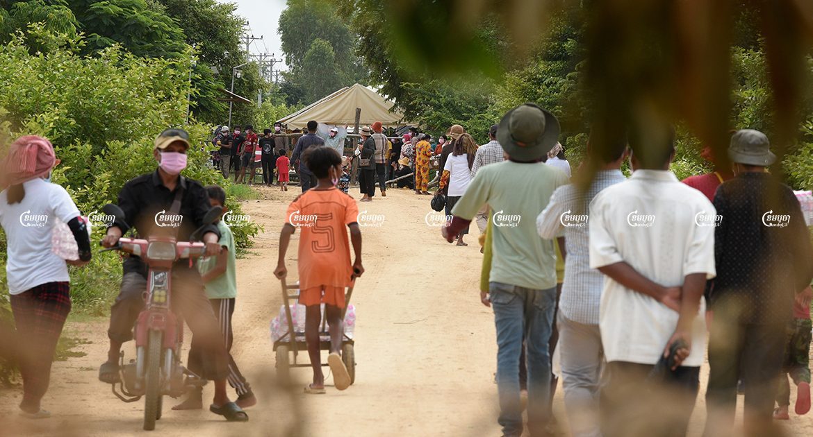 អ្នកភូមិប្រមូលផ្តុំគ្នាធ្វើការតវ៉ានៅមុខរបាំងរបស់នគរបាលទីដែលអាជ្ញាធរបិទផ្លូវចូលទៅដីស្រែរបស់ពួកគាត់ដែលកំពុងត្រូវបានឈូសឆាយ ដើម្បីរៀបចំកន្លែងសម្រាប់គម្រោងសាងសង់ព្រលានយន្តហោះនៅស្រុកកណ្តាលស្ទឹង។ រូបភាពថតកាលពីថ្ងៃទី ១២ ខែកញ្ញា ឆ្នាំ២០២១។ ខេមបូចា/ បញ្ញា ឆព័ណ្ណ