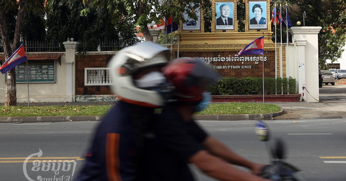 អ្នកធ្វើដំណើរតាមម៉ូតូជិះកាត់អង្គភាពប្រឆាំងអំពើពុករលួយនៅរាជធានីភ្នំពេញនាថ្ងៃទី១៧ ខែធ្នូ ឆ្នាំ២០២១។ (ខេមបូចា/ ព្រីង សំរាំង)