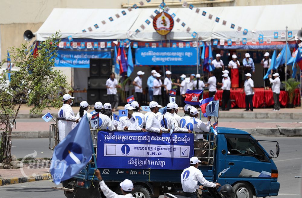 ក្រុមអ្នកគាំទ្រ និងសមាជិកគណបក្សភ្លើងទៀន ដង្ហែក្បួនឃោសនាបោះឆ្នោតជ្រើសរើសសមាជិកក្រុមប្រឹក្សាឃុំ-សង្កាត់ កាត់ពីមុខវេទិកាឃោសនាបោះឆ្នោតរបស់គណបក្សប្រជាជនកម្ពុជា នៅរាជធានីភ្នំពេញ។ រូបថតថ្ងៃទី២១ ខែឧសភា ឆ្នាំ២០២២។ ខេមបូចា/ ព្រីង សំរាំង