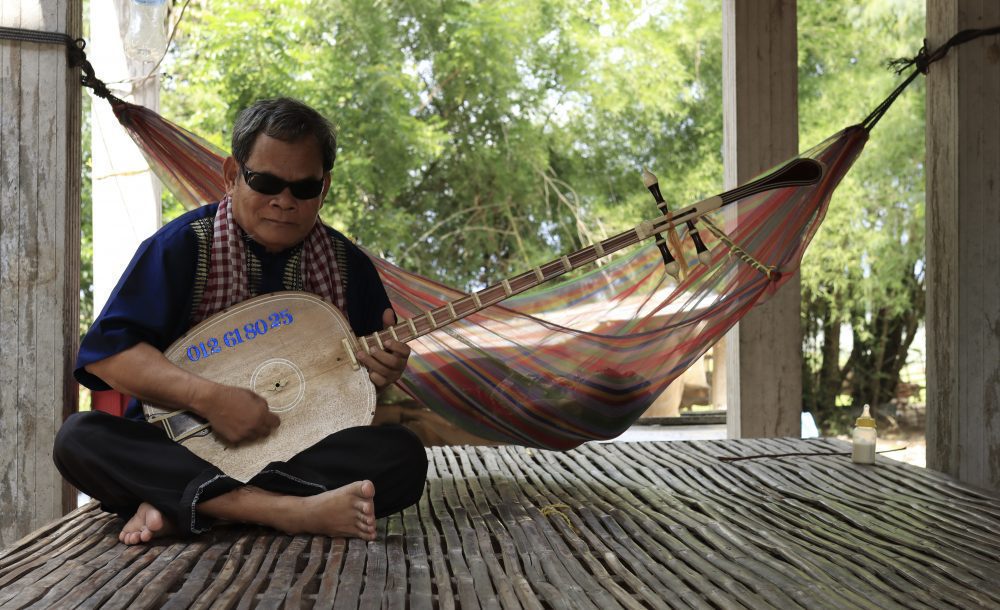 លោកព្រឹទ្ធាចារ្យ ឯ យិន លេងចាប៉ីដងវែងនៅឯផ្ទះរបស់គាត់ក្នុងខេត្តព្រៃវែង។ រូបថតនៅថ្ងៃទី៨ ខែឧសភា ឆ្នាំ២០២២។ ខេមបូចា/ ម៉ិច ជូឡាយ