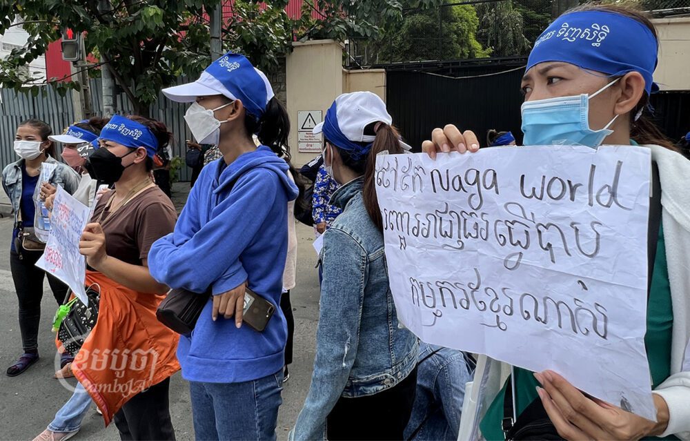 កូដករណាហ្គាវើលដ៍ប្រមាណជាង១០០នាក់បានតវ៉ា ដោយចងក្រណាត់ខៀវលើក្បាលសរសេរថា«កុំយកលុយ ទិញសិទ្ធិ» រួមទាំងលើកបដាទាមទារ ក្បែរស្ថានទូតរុស្សី ផ្លូវសុធារស រាជធានីភ្នំពេញ។ រូបថតនៅថ្ងៃទី២៨ ខែមិថុនា ឆ្នាំ២០២២។ ខេមបូចា/ សុវណ្ណ ស្រីពេជ្រ