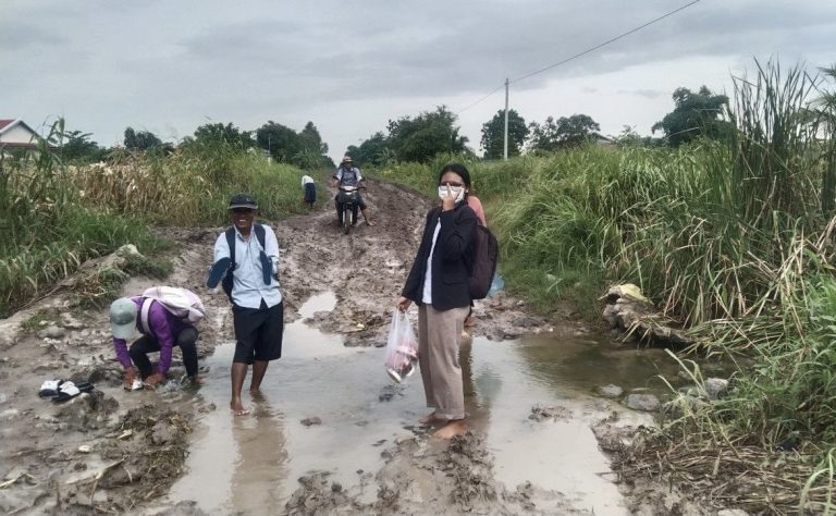 សកម្មភាពអ្នកគ្រូបង្រៀនដើរទៅបង្រៀនសិស្ស ដោះទ្រនាប់ជើងដើរកាត់ផ្លូវដែលមានភក់។ រូបថតនៅថ្ងៃទី៥ ខែតុលា ឆ្នាំ២០២២។ រូបភាពផ្ដល់ឱ្យ