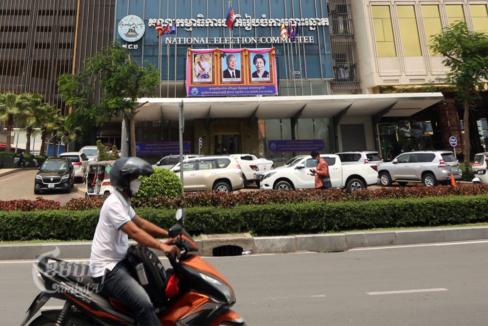 បុរសម្នាក់បើកបរម៉ូតូកាត់មុខគណៈកម្មាធិការជាតិរៀបចំការបោះឆ្នោតក្នុងទីក្រុងភ្នំពេញ កាលពីថ្ងៃទី១១ ខែមេសា ឆ្នាំ២០២២។ ខេមបូចា/ ព្រីង សំរាំង