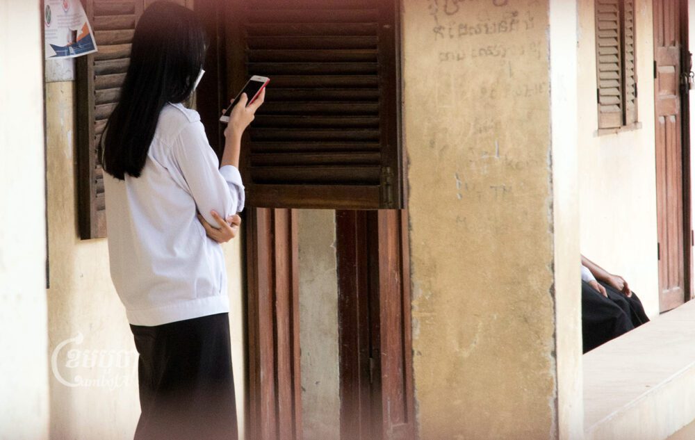 សិស្សស្រីម្នាក់នៃសាលាវិទ្យាល័យមួយកន្លែងក្នុងរាជធានីភ្នំពេញ កំពុងតែចុចទូរសព្ទរបស់ខ្លួននៅមុខថ្នាក់រៀន នៅក្នុងម៉ោងចេញលេង។ រូបថតនៅថ្ងៃទី៣១ ខែមីនា ឆ្នាំ២០២៣។ ខេមបូចា/ អាន វិចិត្រ