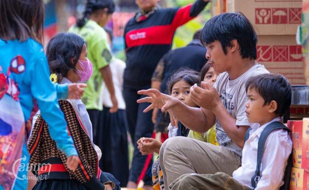 លោក អ៊ុក វណ្ណដេ ស្ថាបនិកសាលាដូងភ្នំគិរីរម្យ កំពុងជជែកជាមួយក្មេងៗ អំឡុងពេលត្រៀមចែកអំណោយ និងសម្ភារ:សិក្សាដល់សិស្សានុសិស្ស កាលព្រឹកថ្ងៃទី៨ ខែធ្នូ ឆ្នាំ២០២៣។ (ខេមបូចា/ ពក ពន្លឺ)