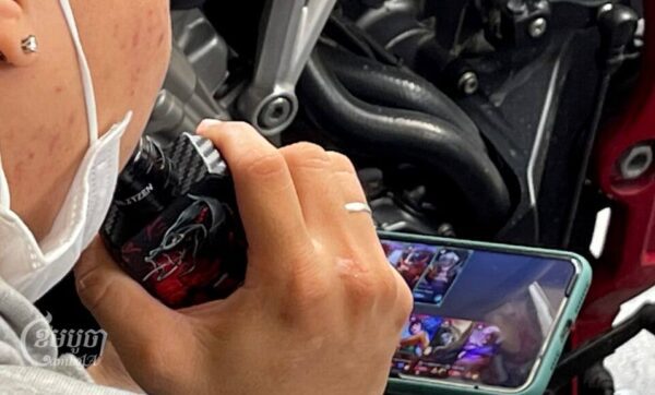 យុវជនម្នាក់កំពុងជក់បារីអេឡិកត្រូនិកនៅក្នុងហាងកាហ្វេមួយកន្លែងក្នុងក្រុងភ្នំពេញ ថ្ងៃទី២៣ ខែធ្នូ ឆ្នាំ២០២២។ (ខេមបូចា/ ព្រីង សំរាំង)