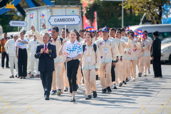 ប្រតិភូ គ្រូបង្វឹក និងកីឡាករ កីឡាការិនីកម្ពុជា ចូលរួមគោរពទង់ជាតិ ក្នុងព្រឹត្តិការណ៍កីឡាស៊ីហ្គេម លើកទី៣៣ ឆ្នាំ២០២៥ នៅប្រទេសថៃ កាលពីថ្ងៃទី៨ ខែធ្នូ ហើយឯកសណ្ឋានដែលពាក់ មានឈ្មោះ NAGAWORLD នេះ កំពុងស្ថិតក្នុងការសង្ស័យថា អាចជាការផ្សព្វ​ផ្សាយ​​ក្រុមហ៊ុនល្បែង ដោយអាជ្ញាធរថៃថា នឹងស៊ើបអង្កេតលើបញ្ហានេះ តែភាគីកម្ពុជាអះអាងថា គ្មានអ្វីខុសច្បាប់កីឡាទេ។ (រូបភាព៖ NOCC)